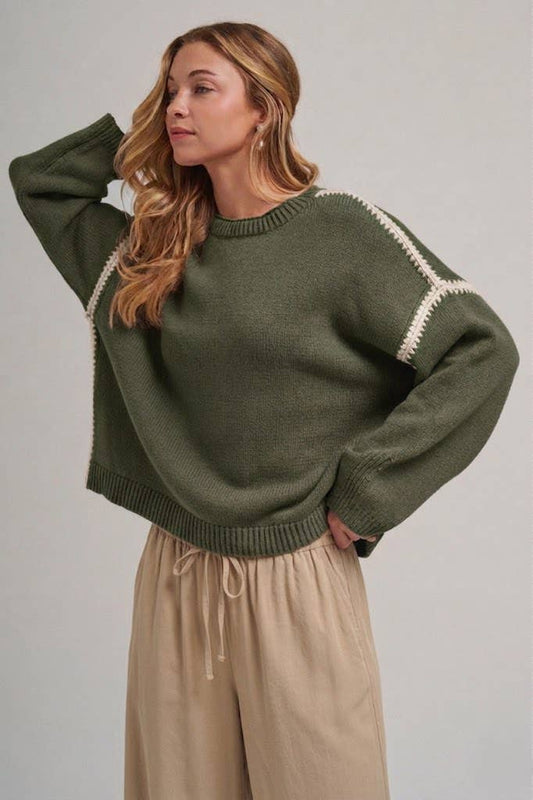 Woman wearing a green sweater with white trim against a plain background