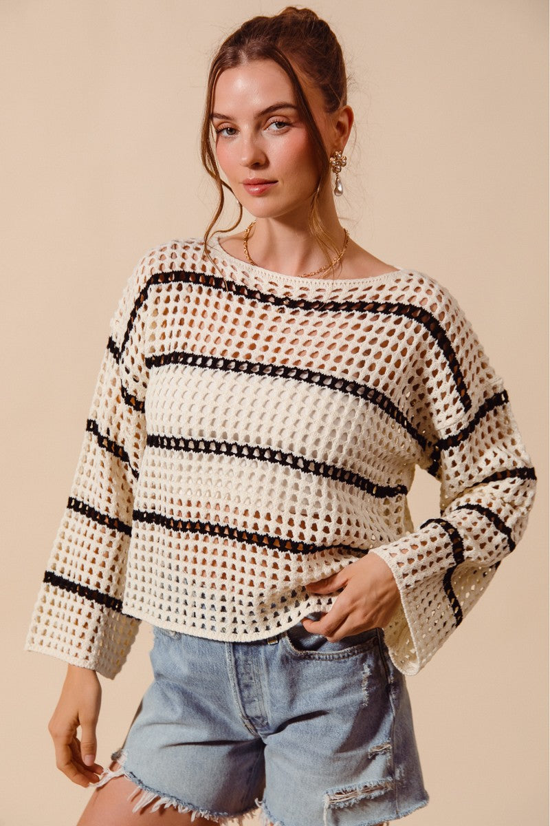 Woman wearing a patterned sweater and denim shorts on a beige background