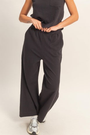 Person wearing black wide-leg pants and a black top on a white background