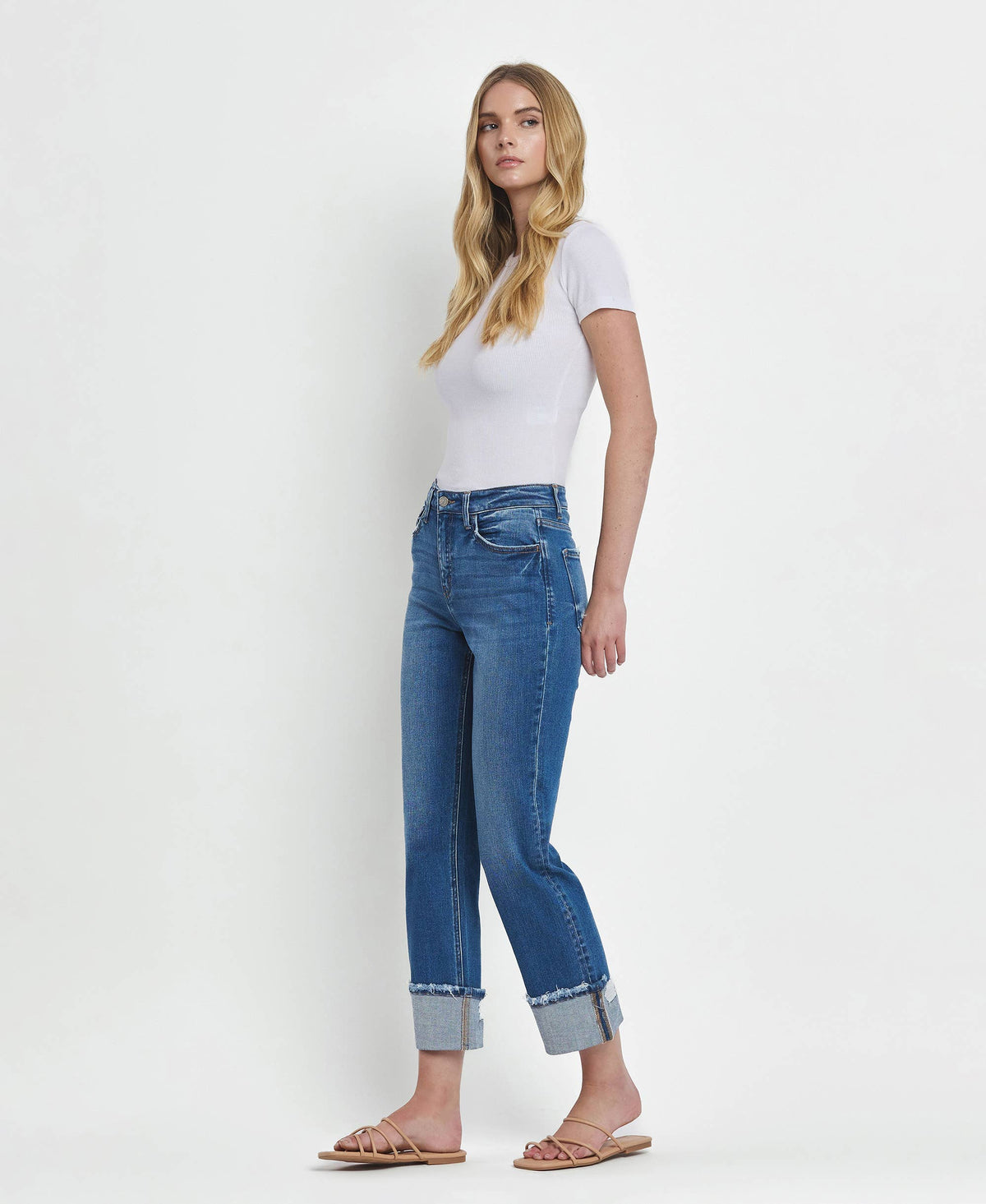 Woman wearing blue jeans and a white top on a white background