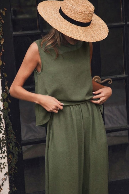 Woman wearing a green dress and straw hat against a dark background
