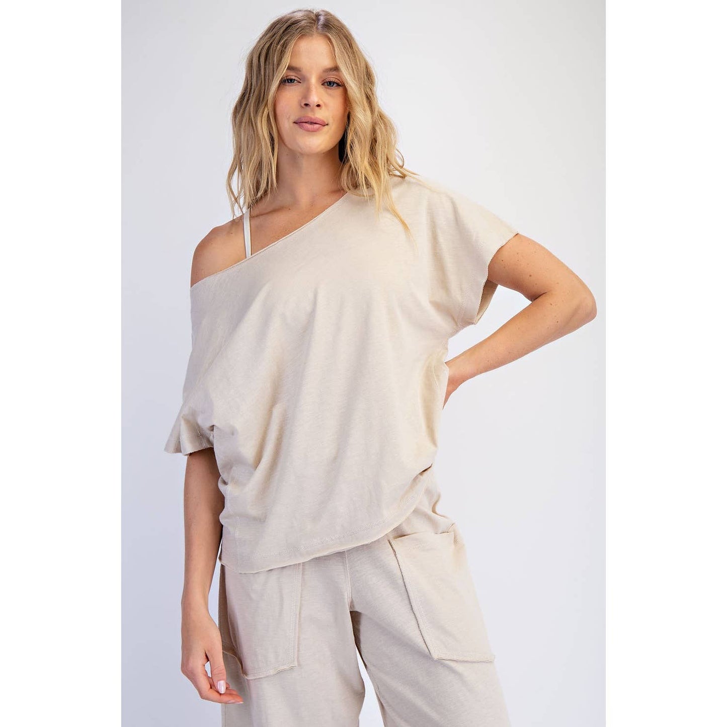Woman wearing a beige off-shoulder top and pants on a white background