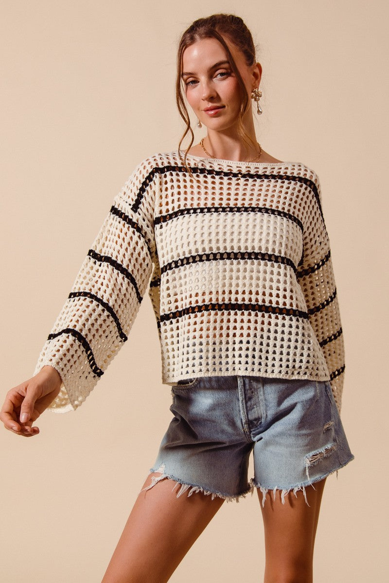 Woman wearing a patterned sweater and denim shorts on a beige background
