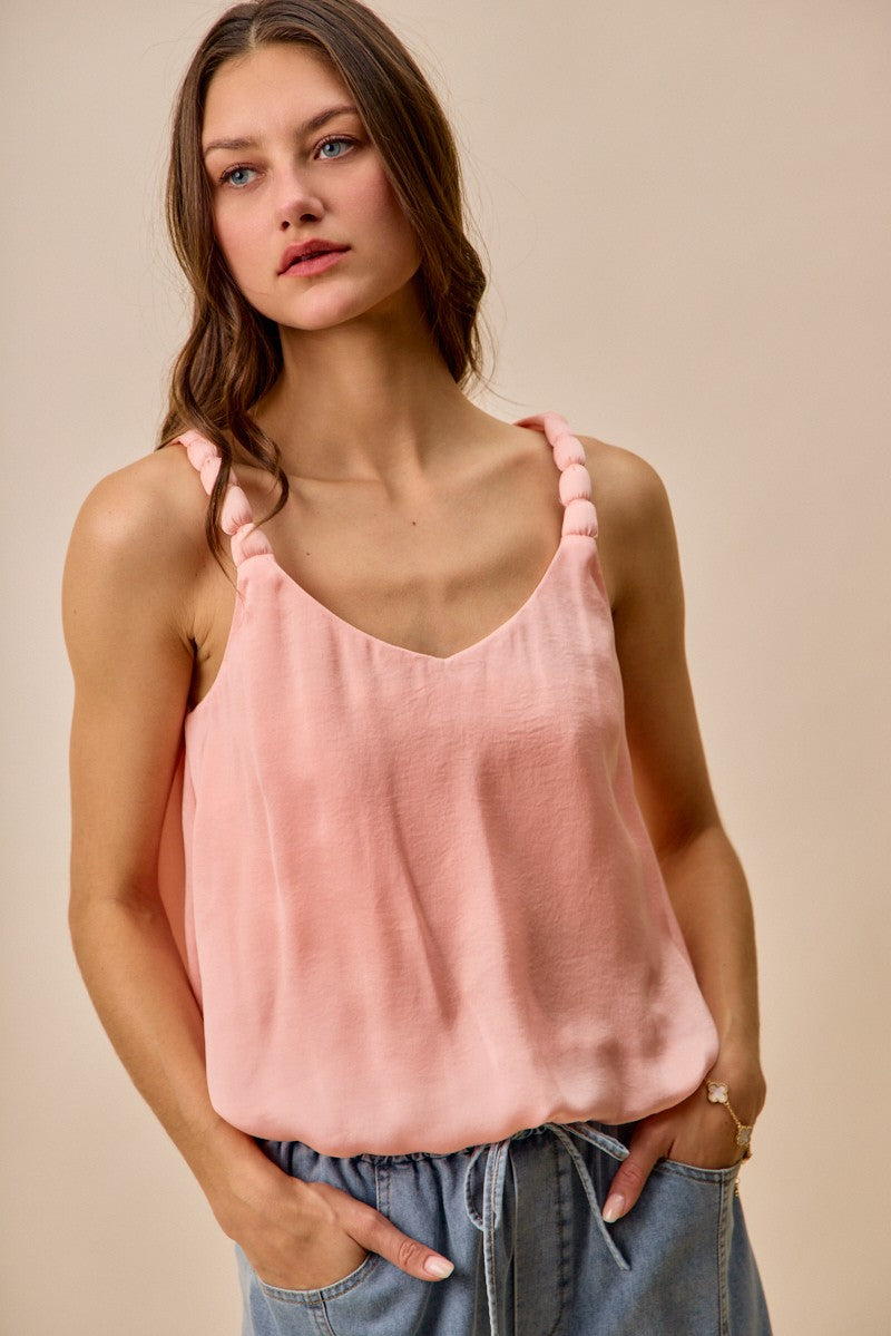 Woman wearing a pink tank top against a beige background