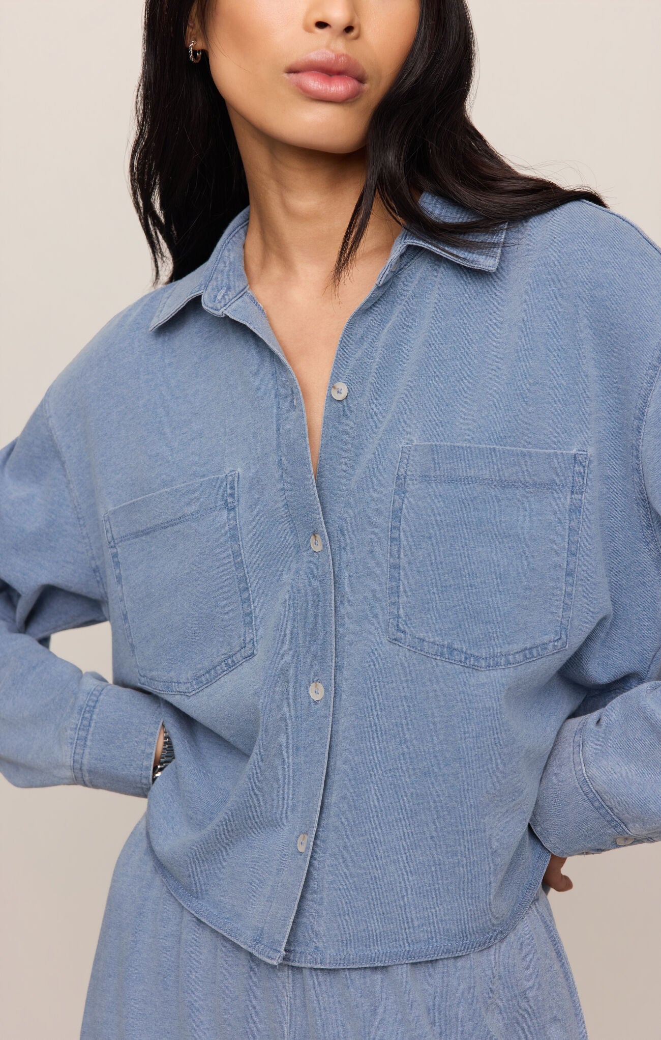 Woman wearing a blue denim shirt against a neutral background