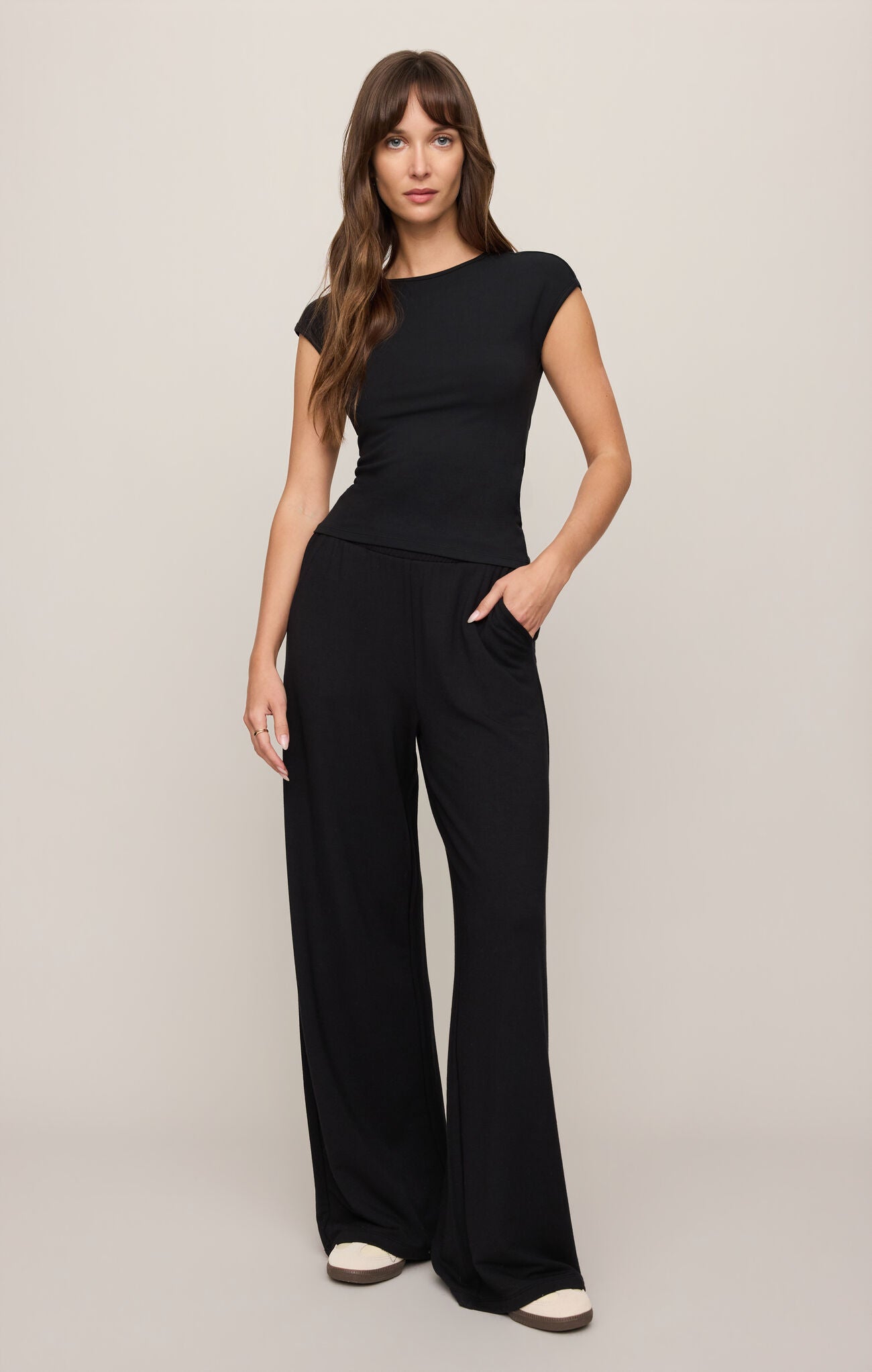 Woman wearing a black jumpsuit on a beige background
