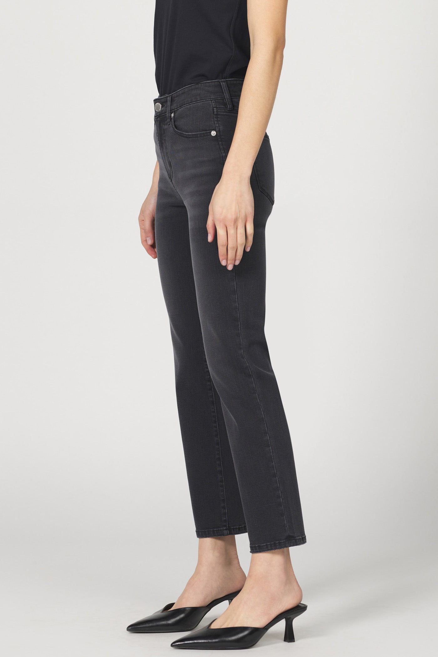 Person wearing black jeans and black shoes on a white background