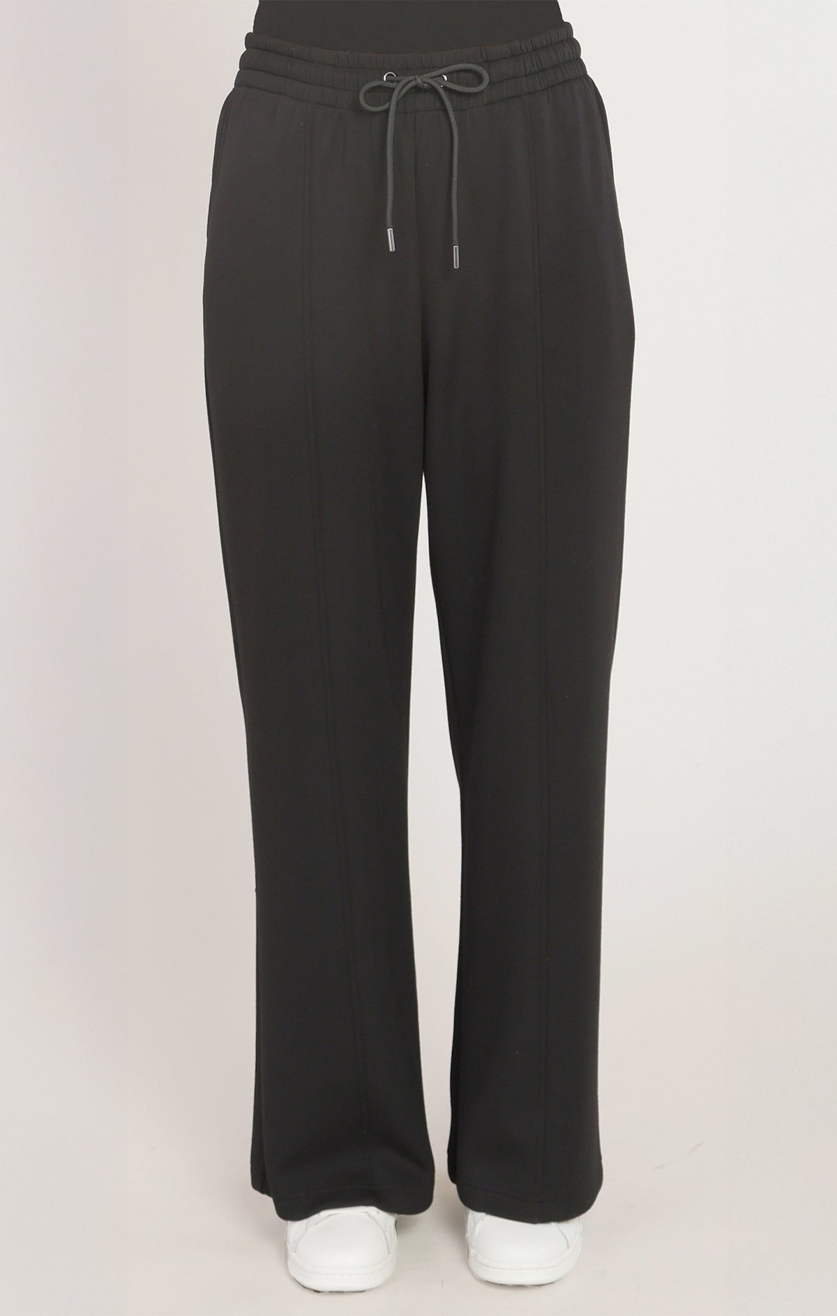 Black pants with a drawstring on a light pink background