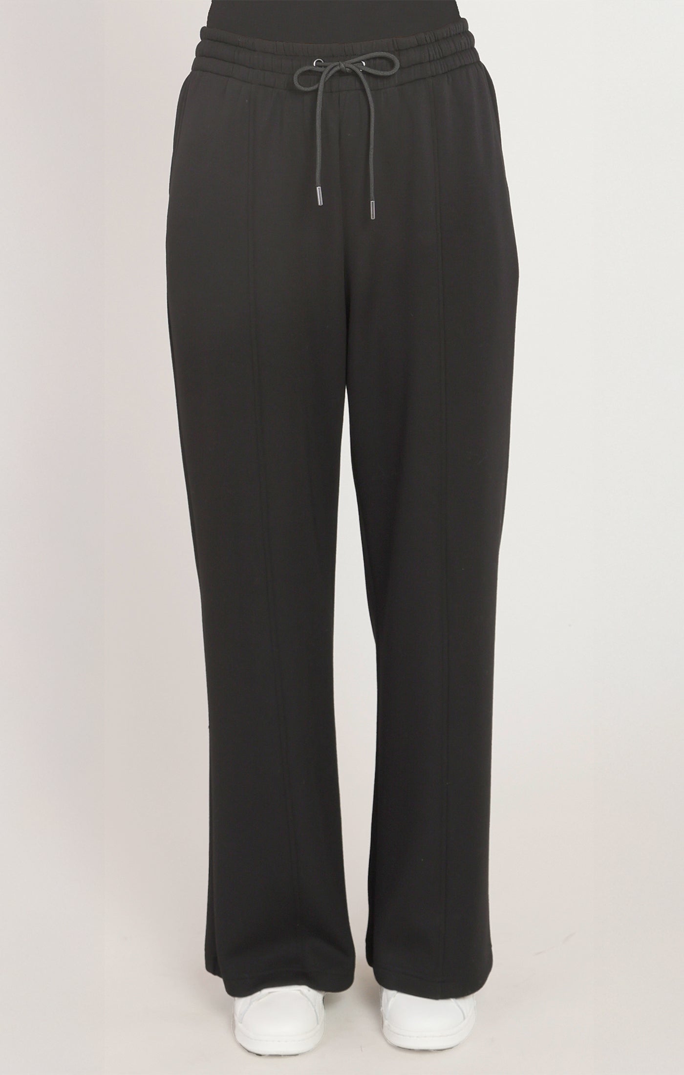 Black pants with a drawstring on a light pink background