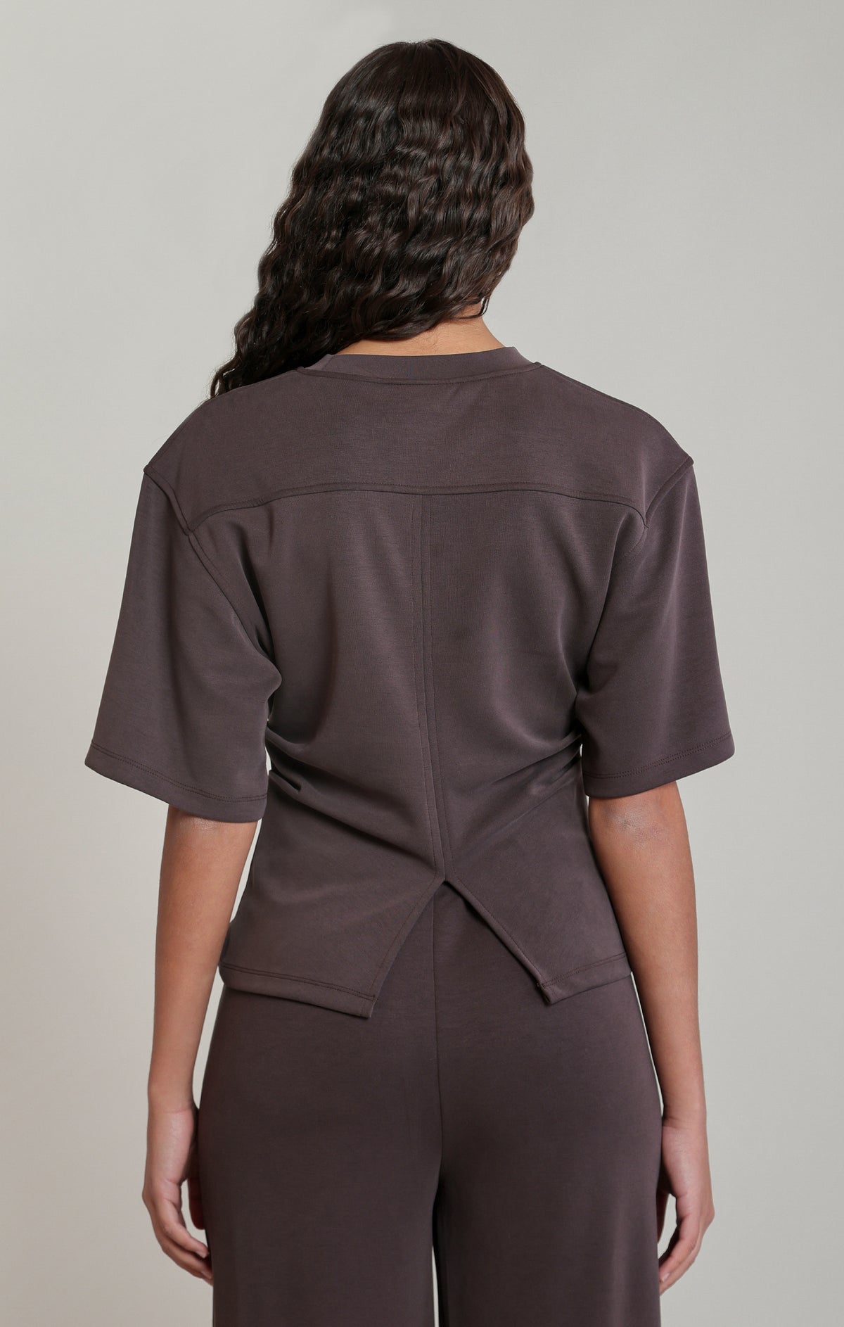 Person wearing a brown outfit with a neutral background