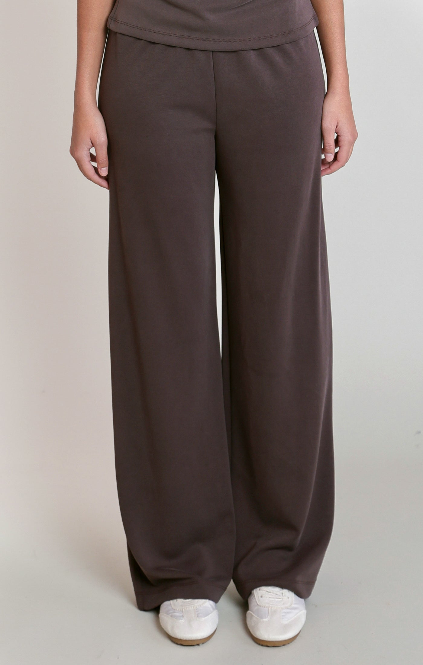 Person wearing brown wide-leg pants on a plain background