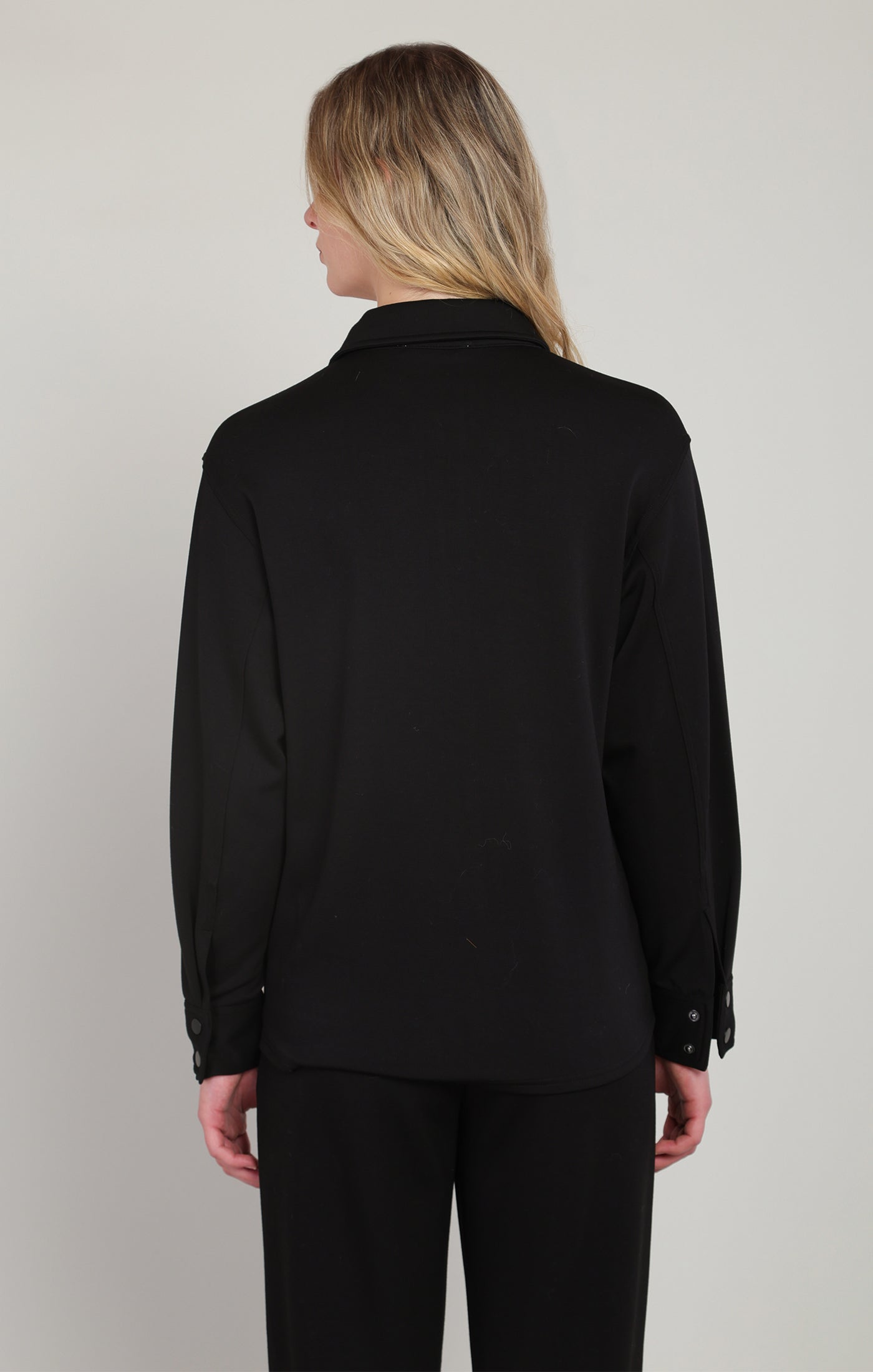 Person wearing a black jacket and pants on a plain background
