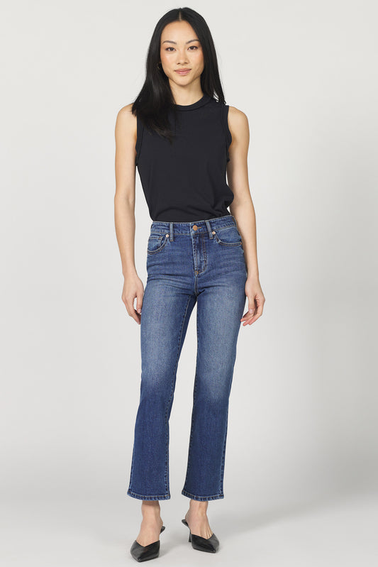 Woman wearing a black sleeveless top and blue jeans on a white background