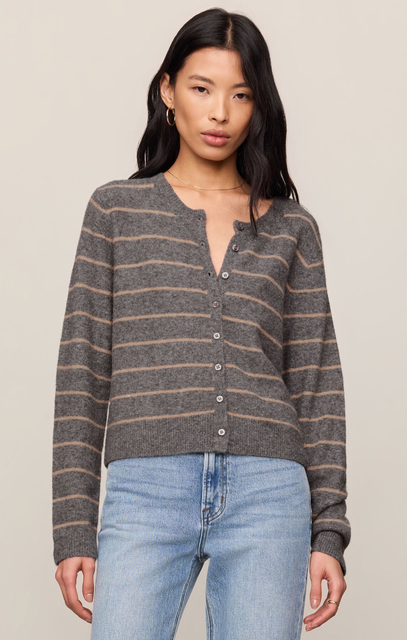 Woman wearing a striped sweater and jeans against a plain background