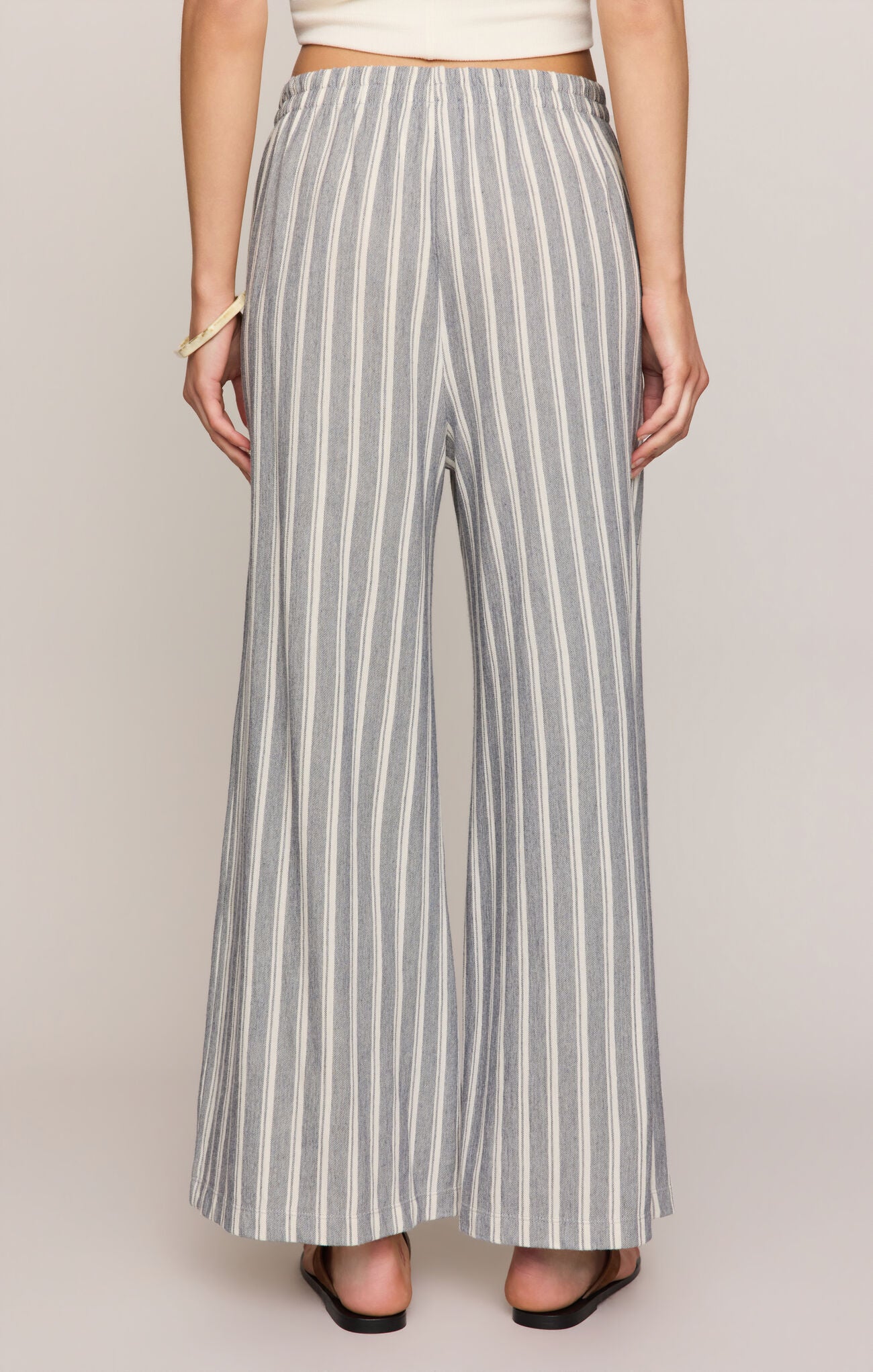 Person wearing gray and white striped wide-leg pants on a plain background