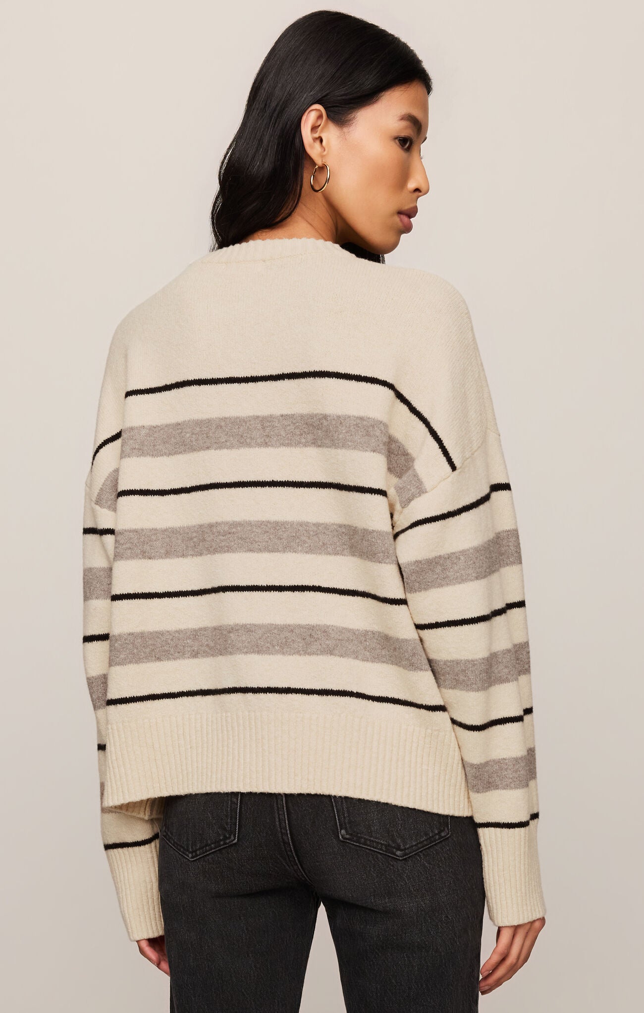 Woman wearing a striped sweater with a neutral background